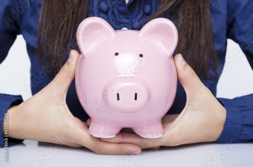 Photo: Close-up of a businesswoman holding a piggy bank Close-up of a businesswoman holding a piggy bank
