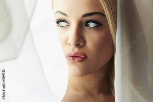 Photo: Beautiful Young Blond Bride Woman. Look in Window.Мeil. Curtains Beautiful Young Blond Bride Woman. Look in Window.Мeil. Curtains