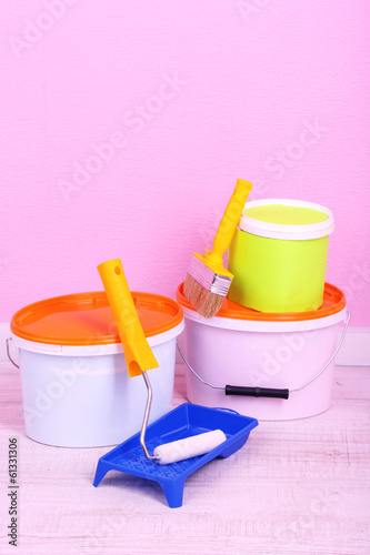 Photo: Paints, roll and paintbrush on floor in room on wall background Paints, roll and paintbrush on floor in room on wall background