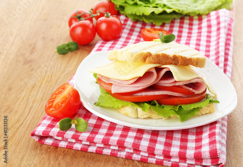 Photo: Tasty sandwich with ham on wooden table Tasty sandwich with ham on wooden table