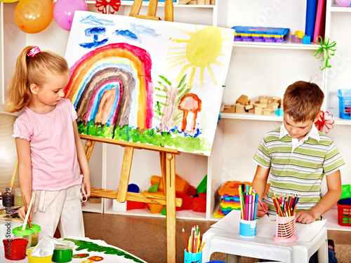 Photo: Child painting at easel. Child painting at easel.