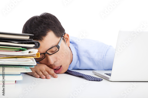 Photo: young businessman too weary to asleep on the desk young businessman too weary to asleep on the desk