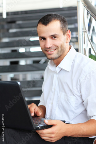Photo: Businessman sitting on stairs and using laptop pc. Businessman sitting on stairs and using laptop pc.