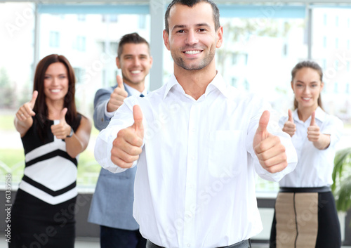 Photo: attractive businessman with team in office showing thumbs up attractive businessman with team in office showing thumbs up
