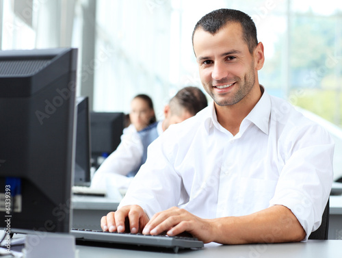 Photo: Casual businessman working in office, sitting at desk Casual businessman working in office, sitting at desk