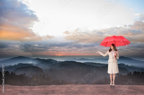 Photo: Composite image of attractive businesswoman holding red umbrella Composite image of attractive businesswoman holding red umbrella