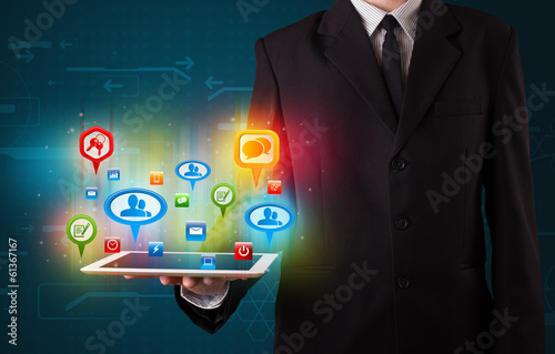 Photo: Businessman presenting modern tablet with colorful social signs Businessman presenting modern tablet with colorful social signs