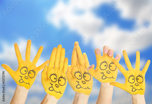 Photo: Painted hands with smile on sky background Painted hands with smile on sky background