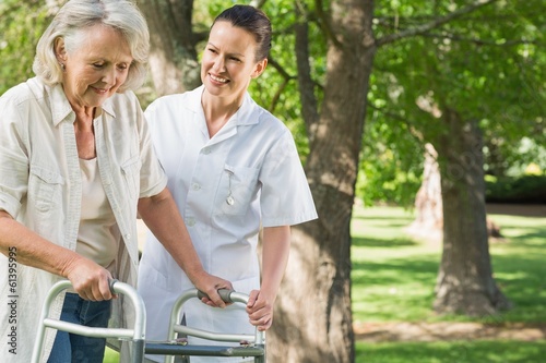 Photo: Female assisting mature woman with walker at park Female assisting mature woman with walker at park