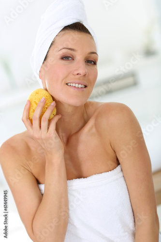 Photo: Attractive woman in bathroom using sponge Attractive woman in bathroom using sponge