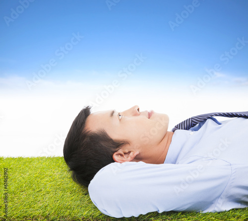 Photo: young businessman lying on a meadow and contemplating young businessman lying on a meadow and contemplating