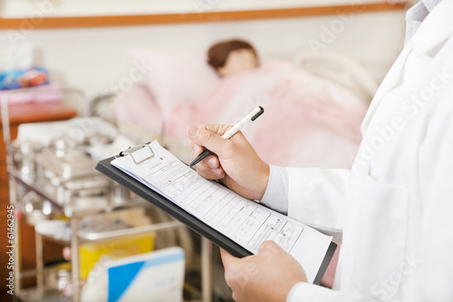 Photo: doctor writing on a medical chart with patient doctor writing on a medical chart with patient