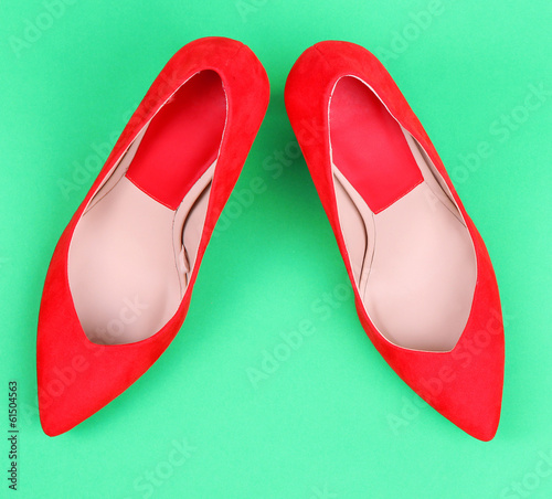Photo: Beautiful red female shoes, on green background Beautiful red female shoes, on green background