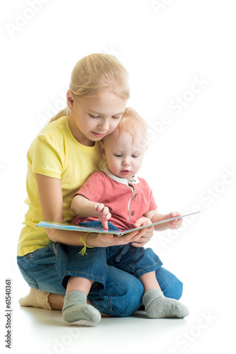 Photo: kid girl playing reading book to her little brother kid girl playing reading book to her little brother