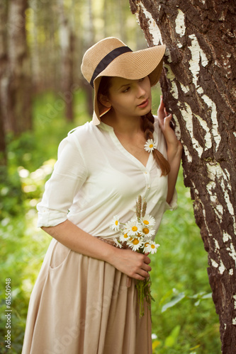 Photo: Beautiful woman with a bouquet of daisies near birch Beautiful woman with a bouquet of daisies near birch