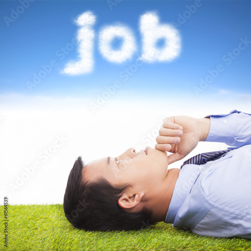 Photo: young businessman thinking on a meadow and cloud shape young businessman thinking on a meadow and cloud shape