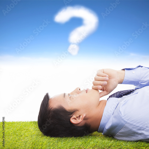 Photo: young businessman thinking with query symbol young businessman thinking with query symbol