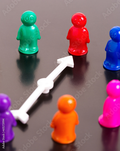 Photo: Group of toy people and white arrow pointing on the red one Group of toy people and white arrow pointing on the red one