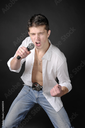 Photo: Expressively man singing with microphone on dark background. Expressively man singing with microphone on dark background.