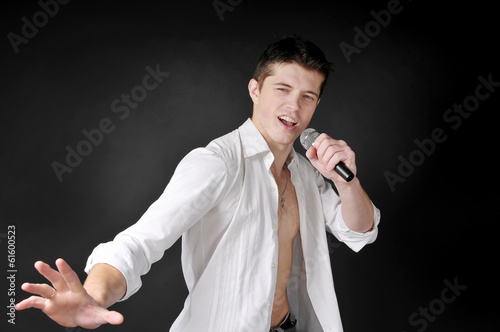 Photo: Expressively man singing with microphone on dark background. Expressively man singing with microphone on dark background.