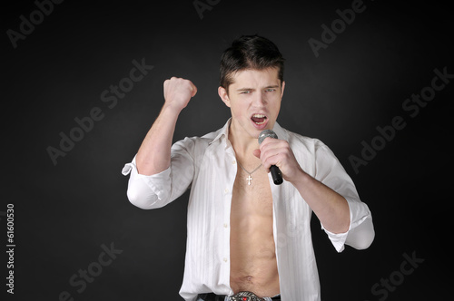 Photo: Expressively man singing with microphone on dark background. Expressively man singing with microphone on dark background.