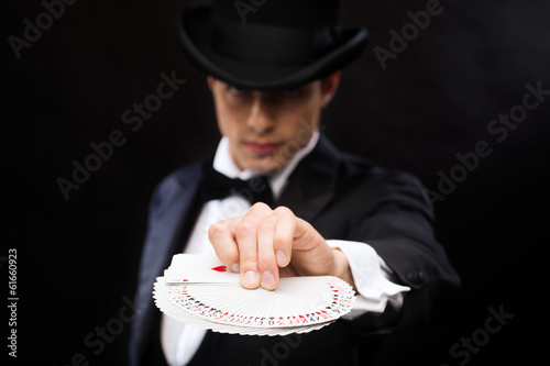 Photo: magician in hat showing trick with playing cards magician in hat showing trick with playing cards