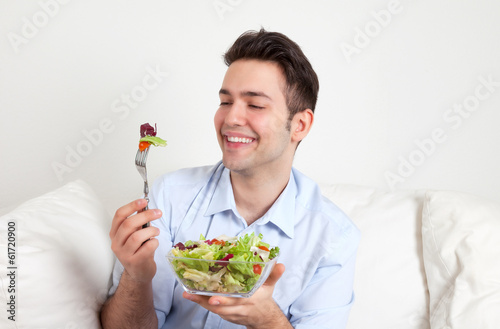 Photo: Lachender junger Mann freut sich über seinen Salat Lachender junger Mann freut sich über seinen Salat