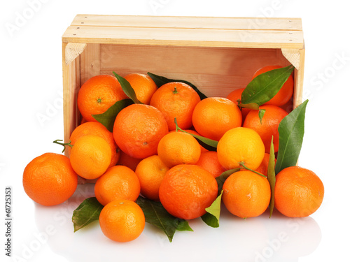Photo: Ripe tasty tangerines with leaves in wooden box dropped Ripe tasty tangerines with leaves in wooden box dropped