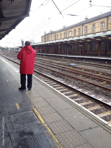 Instant Collection: Man in red jacket waiting at a train station platform Man in red jacket waiting at a train station platform