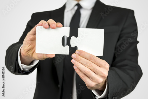 Photo: Businessman holding two puzzle pieces Businessman holding two puzzle pieces