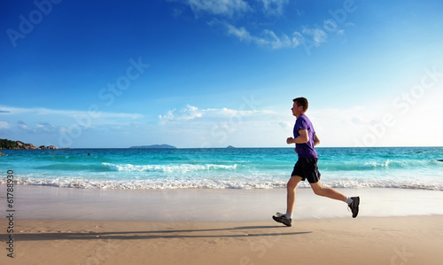 Photo: Man running on tropical beach at sunset Man running on tropical beach at sunset
