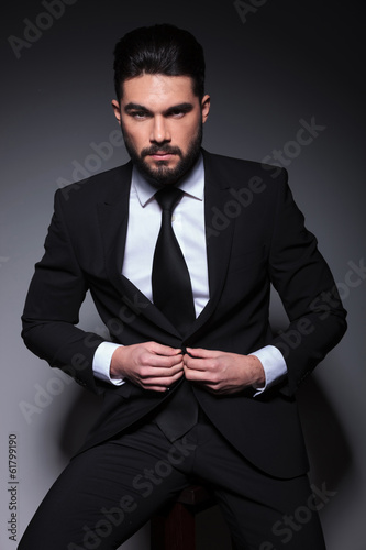 Photo: young fashion man looks at you and buttons suit young fashion man looks at you and buttons suit