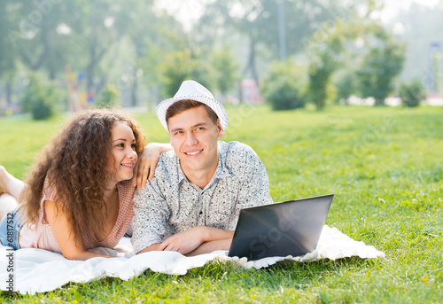 Photo: couple lying together in a park with laptop couple lying together in a park with laptop