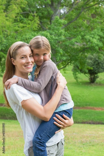 Photo: Smiling mother carrying daughter at park Smiling mother carrying daughter at park