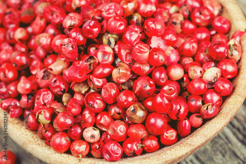 Photo: pink peppercorn in a spoon on wooden background pink peppercorn in a spoon on wooden background