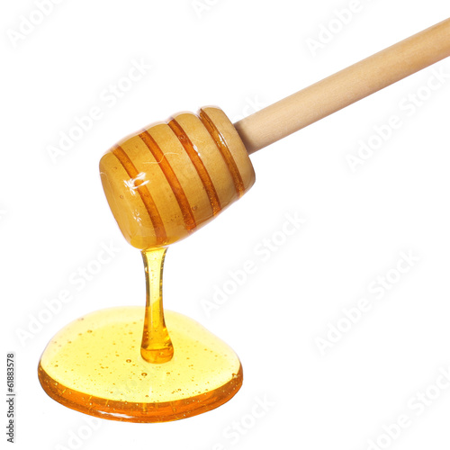Photo: Honey dripping from wooden honey dipper isolated on white Honey dripping from wooden honey dipper isolated on white