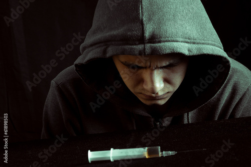 Photo: Grunge image of a depressed drug addict looking at a syringe Grunge image of a depressed drug addict looking at a syringe