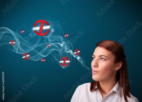 Photo: Young woman smoking dangerous cigarette with no smoking signs Young woman smoking dangerous cigarette with no smoking signs