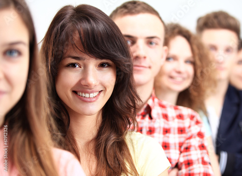 Photo: Young woman standing in front of young people standing in a row Young woman standing in front of young people standing in a row