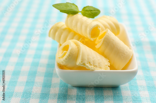 Photo: Curls of fresh butter with basil in bowl, on blue tablecloth Curls of fresh butter with basil in bowl, on blue tablecloth