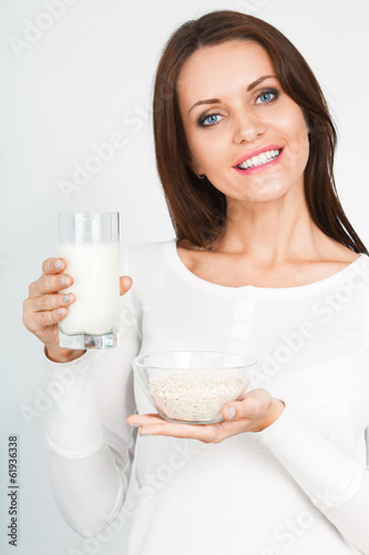 Photo: woman holding glass of mik and bowl with oatmeal woman holding glass of mik and bowl with oatmeal