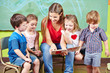 Kinder mit Erzieher lesen Buch im Kindergarten Kinder mit Erzieher lesen Buch im Kindergarten