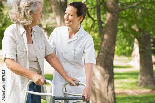 Photo: Woman assisting mature female with walker at park Woman assisting mature female with walker at park
