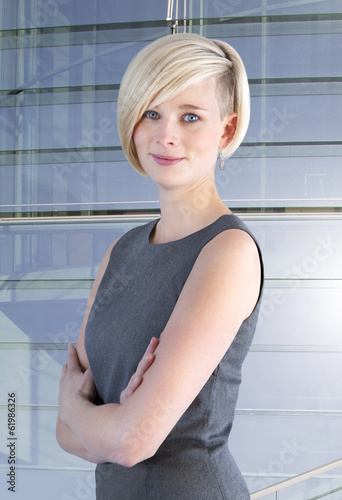 Photo: Young woman stands in front of glass facade Young woman stands in front of glass facade