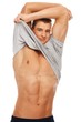 Handsome young man taking off grey t-shirt Handsome young man taking off grey t-shirt