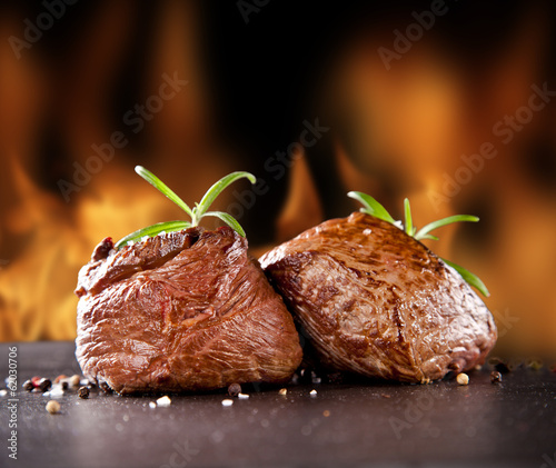Photo: Fresh beef steaks on black stone and fire Fresh beef steaks on black stone and fire