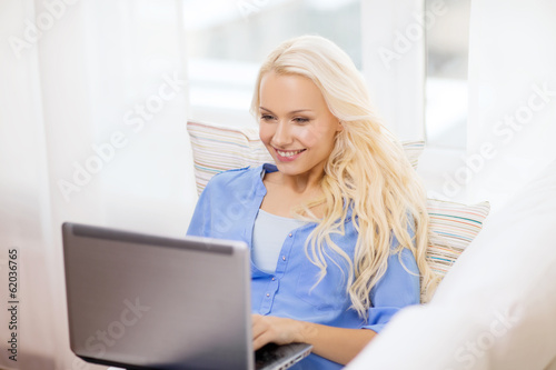Photo: smiling woman with laptop computer at home smiling woman with laptop computer at home