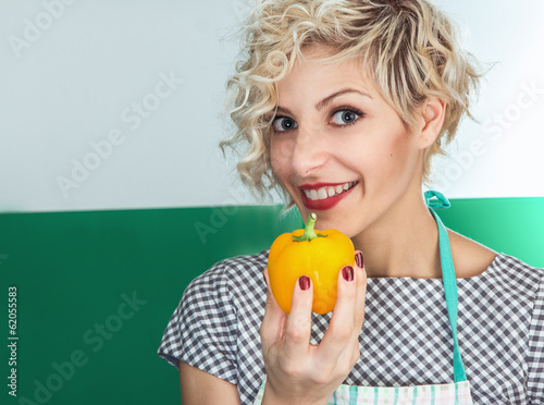 Photo: Young smiling woman cook holding pepper Young smiling woman cook holding pepper