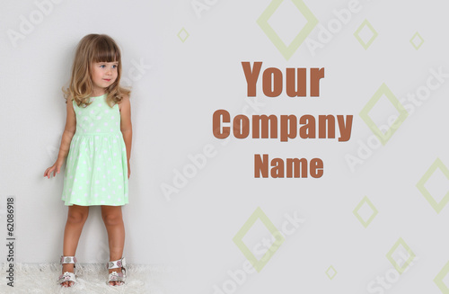 Photo: Little cute girl on carpet, on gray background Little cute girl on carpet, on gray background