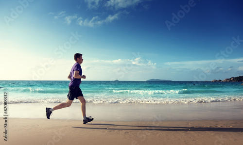 Photo: Man running on tropical beach at sunset Man running on tropical beach at sunset